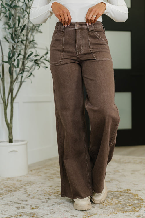 Person wearing brown wide-leg pants and a white shirt indoors.