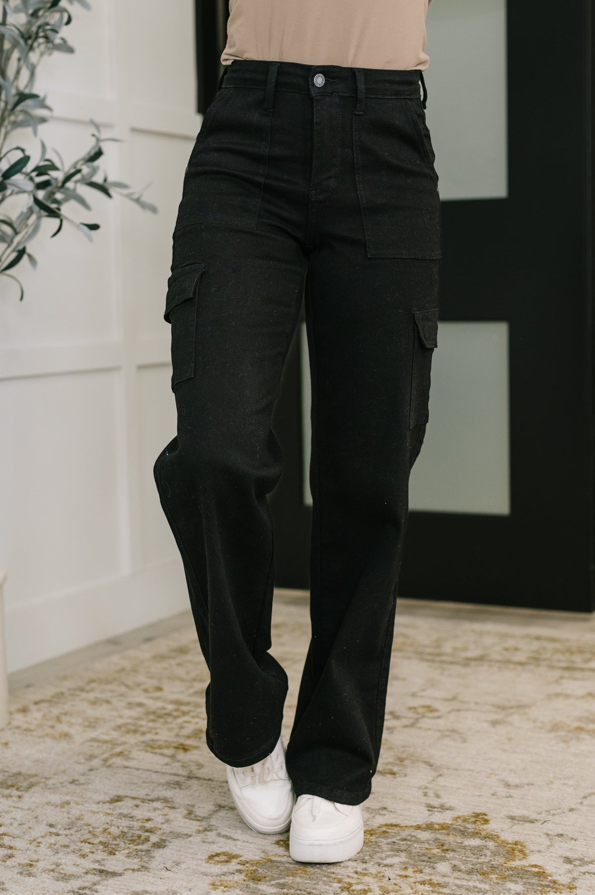 Person wearing black cargo pants with a neutral background