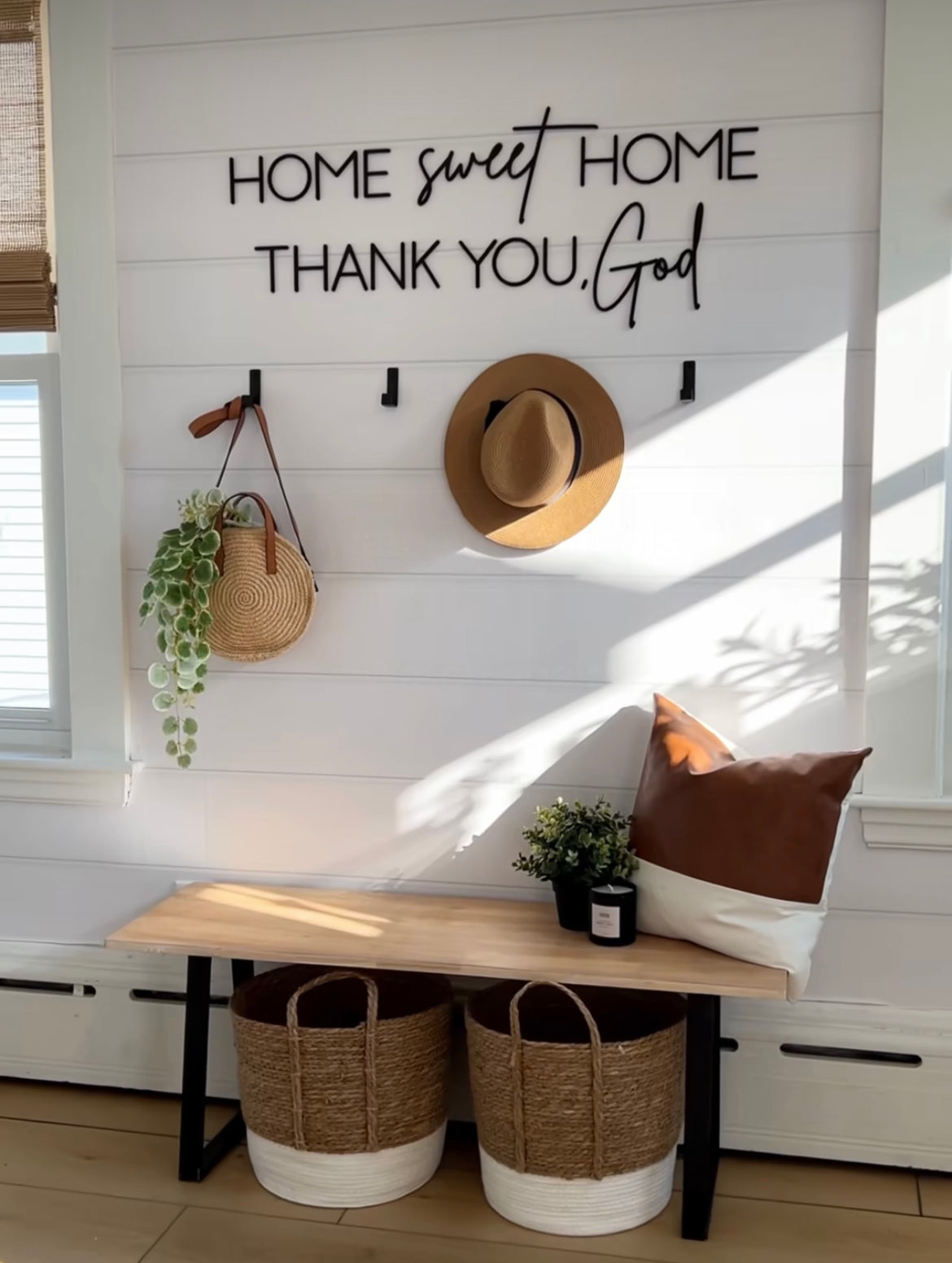 Nestled nook with 'Home sweet home thank you God' sign, wooden bench, baskets, and decor items.